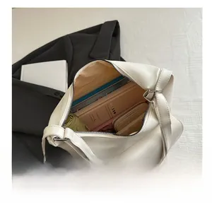 Spacious interior of white PU leather tote bag showing items like books and umbrella