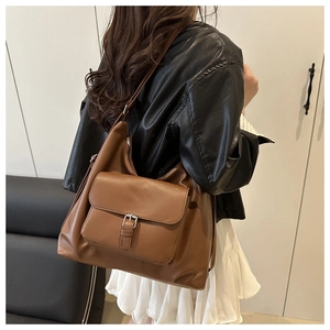 Borsa tote in ecopelle marrone con tasca a fibbia indossata da modella per dimensione