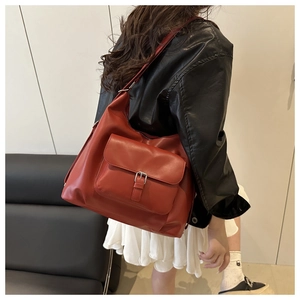 Dettaglio della borsa tote in pelle rosso mattone con fibbia argentata indossata da modella