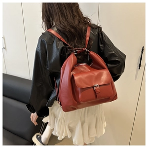 Modella che indossa uno zaino in pelle marrone rosso con dettaglio fibbia argento da dietro