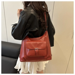 Dettaglio di borsa a spalla rosso mattone vintage con fibbia metallica indossata da modella