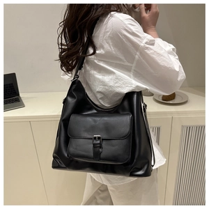 Vista laterale di una grande borsa a spalla in finta pelle nera opaca con fibbia