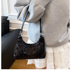 Model carrying a black sequined crescent hobo bag for stylish evening shoulder wear