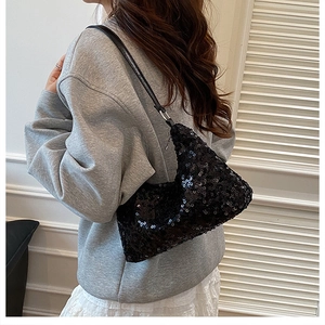Detail of stylish black sequin shoulder bag showing dense glitter and leather strap