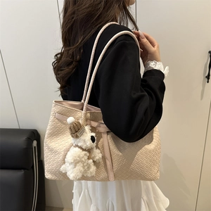 Sac fourre-tout tressé beige à la mode avec un charme de chien en peluche sur un mannequin