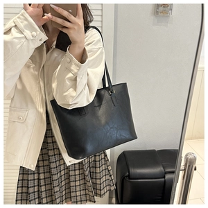 Close-up of black leather tote bag with embossed text and dual handle detail
