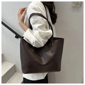 Detail of dark brown tote bag with vintage texture on white shirt background