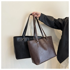 Detail of vintage textured leather tote bags in black and dark brown with logo embossing