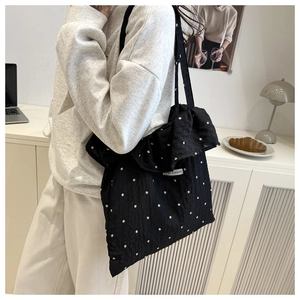 Dettaglio borsa tote in rete nera con stampe floreali a margherite e bordi a balze
