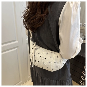 Close-up of white jacquard dumpling bag featuring small black bows and a knotted strap