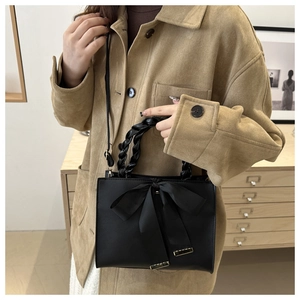 Detail of black square handbag with silk bow and unique braided handle feature