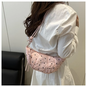 Detailed side view of pink crescent shoulder bag with black rabbit and bow embroidery
