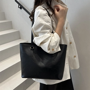 Minimalist black large capacity tote bag shown on model in a stylish lifestyle setting