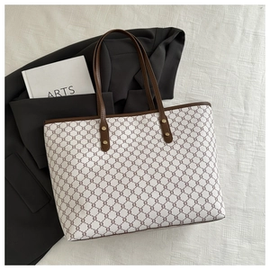 Top-down view of a classic tote bag with leather straps on a striped fabric background