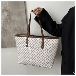 Detailed close-up of a vintage monogram tote bag with brown leather handles and gold rivets