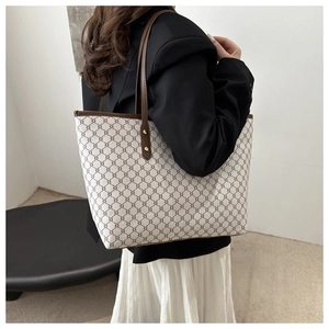 Detail view of canvas tote bag with vintage pattern and brown leather straps on model
