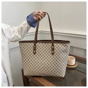 Close-up of geometric pattern tote bag with leather handles and metallic rivet details