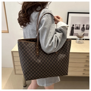 Close-up of vintage brown monogram tote bag with leather strap and golden rivets