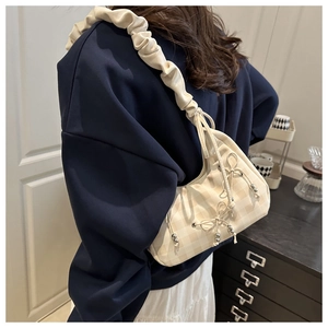 Detail of cream checkered underarm bag featuring ruffled shoulder strap and bow