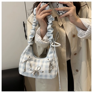 Close-up of blue checkered pattern bag with ruffled handle and silver bow charms