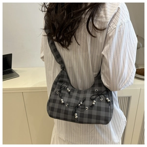 Detail of grey checkered hobo bag with ribbon bow and metal beads on a model