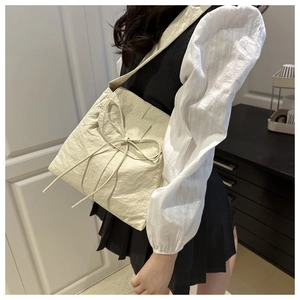 Beige nylon tote bag detail featuring large decorative bow and pleated texture