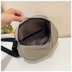 Detailed interior of a light grey nylon crossbody bag showing main pouch and zipper pocket