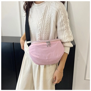 Detail of pink crescent bag with dual zippers and adjustable black shoulder strap