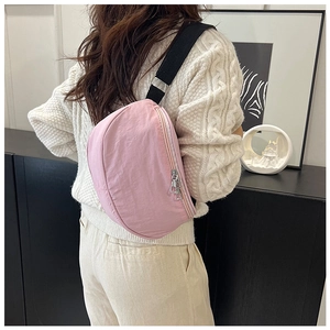 Detailed back view of pink nylon crescent crossbody bag worn by a model in a modern room