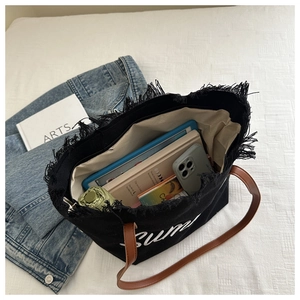 Gros plan du sac fourre-tout noir montrant l'intérieur spacieux avec tablette et livres