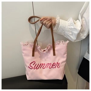 Détail du sac fourre-tout en toile rose avec broderie Summer et bordures à franges