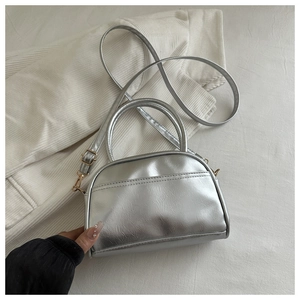 Close-up of metallic silver shell bag featuring dual handles and fine leather texture