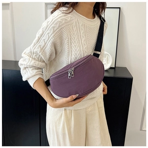 Detail showing purple nylon crescent crossbody bag with silver zippers and black strap