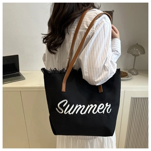 Dettaglio della borsa tote in tela nera con ricamo Summer bianco e manici in cuoio