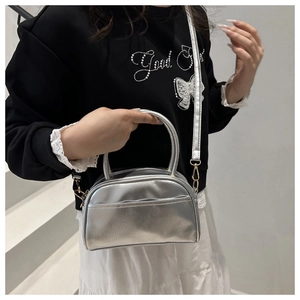 Chic silver crossbody pillow bag with metallic finish and gold hardware on model