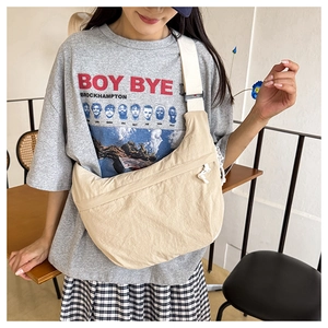 Crossbody wear display of a beige nylon crescent bag on a model showing size and drape