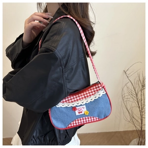 Détail de bordure à carreaux rouges et dentelle blanche sur un sac à main en jean