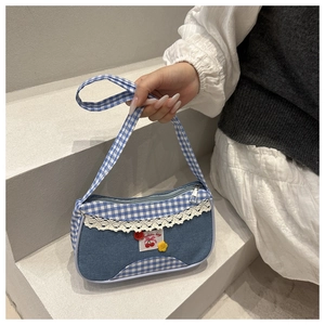 Détail du sac à main en denim à carreaux bleus avec dentelle blanche et motifs floraux
