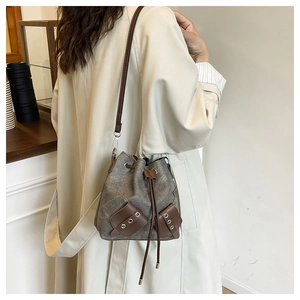 Detailed view of a retro drawstring bucket bag featuring brown contrast pockets and strap