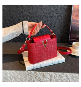 Gros plan sur la texture pailletée rouge et le fermoir en V doré du sac à main chic