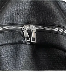 Detail of smooth silver double zippers and metal M logo on black lychee leather backpack