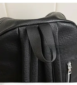 Close-up of a black backpack featuring reinforced top handle and lychee grain texture