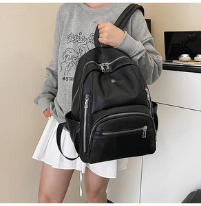 Detailed view of black litchi texture backpack with multiple functional zipper pockets