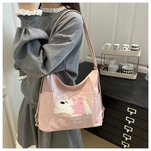 Detail of pink shoulder bag featuring a cute plush puppy embroidery and Happy Puppy text