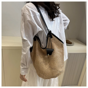 Detailed back view of a beige woven tote bag with black leather shoulder straps on a model