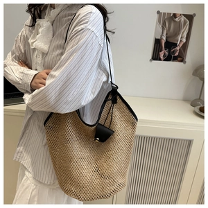 Close-up of woven straw tote bag featuring contrast black leather trim and drawstring detail