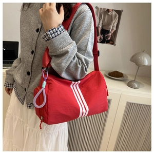 Macro shot of red cylindrical sports bag featuring three vertical white stripes and cord