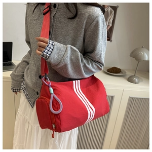 Detail of red striped barrel bag with adjustable nylon strap and woven rope accent