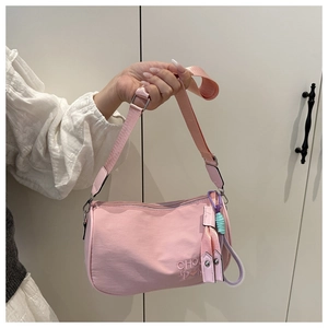 Detailopname van de roze halvemaanvormige tas met borduursel en kleurrijke knoop hanger