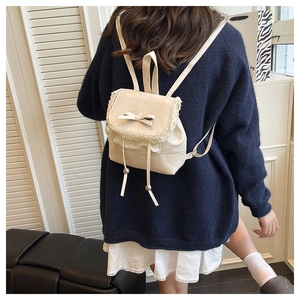 Detail of a beige ballet-style mini backpack with bow decoration and lace edges